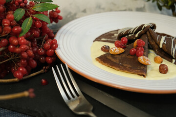 
Pancakes made of white and dark chocolate, decorated with viburnum berries. Sweet pancakes for kids. Shrovetide, Slavic holidays, Traditional flour dishes.