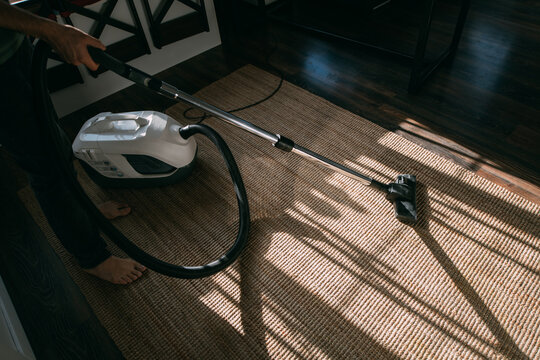House Cleaning. Vacuum Cleaner Standing On Jute Carpet In Sunlight