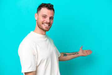 Young Brazilian man isolated on blue background extending hands to the side for inviting to come