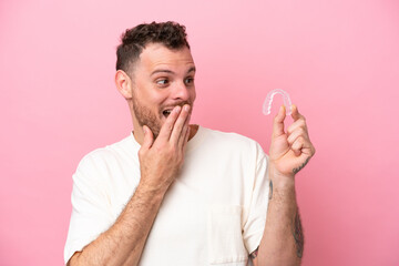 Brazilian man holding invisible braces with surprise and shocked facial expression