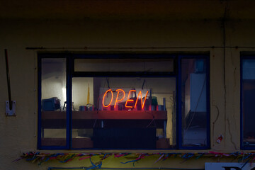 A neon red open sign in a dark shop window - Powered by Adobe