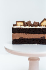 Chocolate cake with cream sponge cake decorated with cookies stands on a white stand on a white background. Isolated background. A tasty treat for a children's birthday party. Pastry craftsmanship.