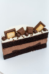 Chocolate cake with cream sponge cake decorated with cookies stands on a white stand on a white background. Isolated background. A tasty treat for a children's birthday party. Pastry craftsmanship.