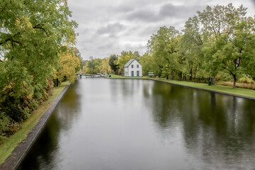 One of the Merrickville boat locks on the Rideau Canal system in autumn showing lock full of water on a cloudy day, lock house in background, dark sky, daytime, nobody