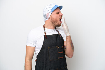 Fishmonger man wearing an apron isolated on white background yawning and covering wide open mouth with hand