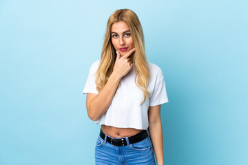 Young Uruguayan blonde woman over isolated blue background thinking