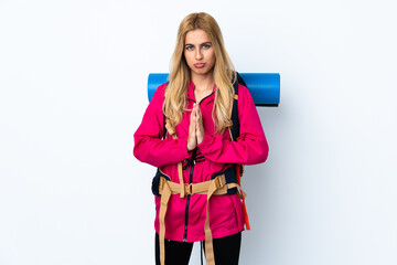 Young mountaineer woman with a big backpack over isolated white background pleading