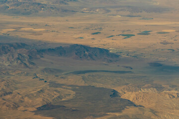 Aerial view of the deserts in the western United States featuring Canyons, rock formations, clouds and parceled farmland