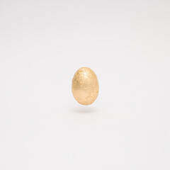 Easter creative layout made with golden Easter egg levitating on a white background. Minimal holiday still life concept.