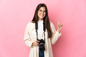 Young photographer Brazilian girl isolated on pink background pointing up a great idea - obrazy, fototapety, plakaty