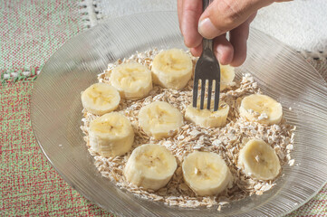 flaked oats and sliced banana, on a plate that is on a table with natural light,copy space in several parts