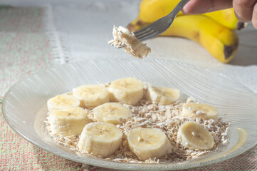 flaked oats and sliced banana, on a plate that is on a table with natural light,copy space in several parts