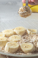 flaked oats and sliced banana, on a plate that is on a table with natural light,copy space in several parts