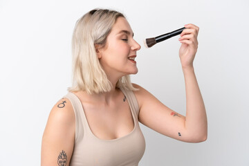 Fototapeta premium Young caucasian woman isolated on white background holding makeup brush and whit happy expression