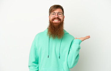 Young reddish caucasian man isolated on white background holding copyspace imaginary on the palm to...