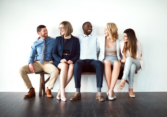 Obraz premium So what are you guys doing today. Shot of a group of work colleagues seated next to each other against a white background.