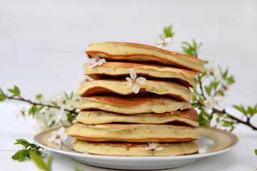 lush pancakes and plum blossom branch on the table close-up