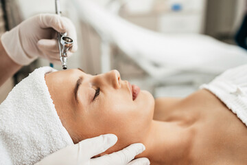 Obraz na płótnie Canvas Beautiful brunette getting oxygen face therapy in a beauty salon. Professional skin care treatment.
