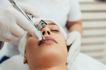 Obraz na płótnie Canvas Beautiful brunette getting oxygen face therapy in a beauty salon. Professional skin care treatment.