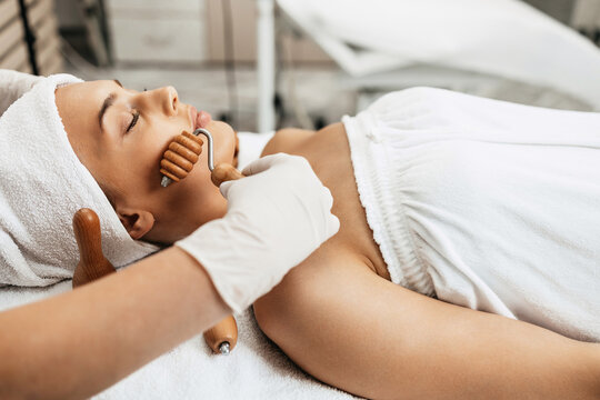 Beautiful brunette getting face maderotherapy in a beauty salon. Professional skin care treatment.