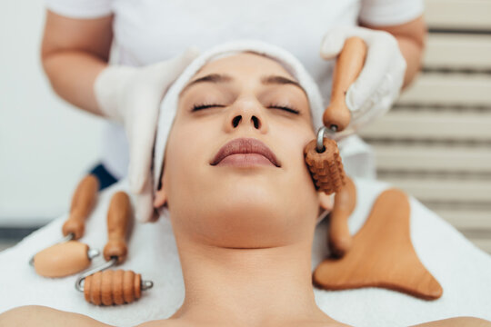 Beautiful brunette getting face maderotherapy in a beauty salon. Professional skin care treatment.