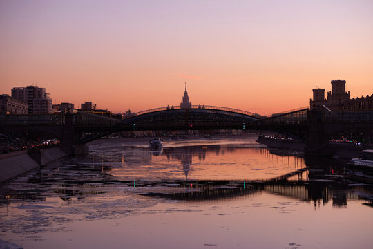 Urban landscape with beautiful red sunset on Moscow River and Moscow State University at far after the bridge