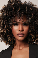 Vertical photo of beautiful young woman with curly black hair posing on white.