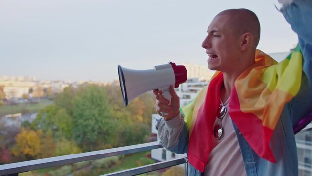 Angry European bald non-binary person screaming via megaphone, fighting for their rights to live equally. LGBTQAI Rights Concept. High quality 4k footage
