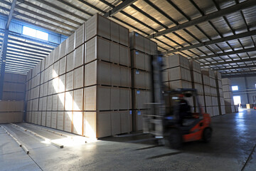 Workers drive forklifts to transport density board products in the factory, North China