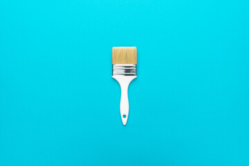 Paint brush on the turquoise blue background. Minimalist photo of white brush central composition.