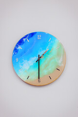 Vintage clock handcrafted from wood and epoxy resin. Clock in the form of an ocean shore and a sandy beach. Multi-colored stains of epoxy resin in the form of a finished product.