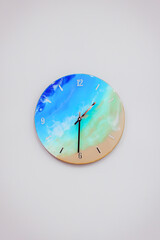 Vintage clock handcrafted from wood and epoxy resin. Clock in the form of an ocean shore and a sandy beach. Multi-colored stains of epoxy resin in the form of a finished product.