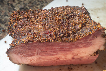 Roasted beef, pastrami on slate cutting board, male hand holding a piece of pastrami,Copy space.