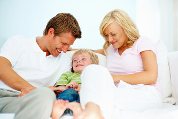 Family of three sitting on sofa. Happy couple sitting on a sofa with their young son.