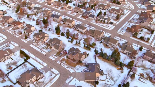 Winter, suburban neighborhood with partial snow covering, moving aerial view.
