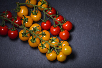 Fototapeta na wymiar Mini red and yellow tomatoes on a dark background scenarios. Food photography
