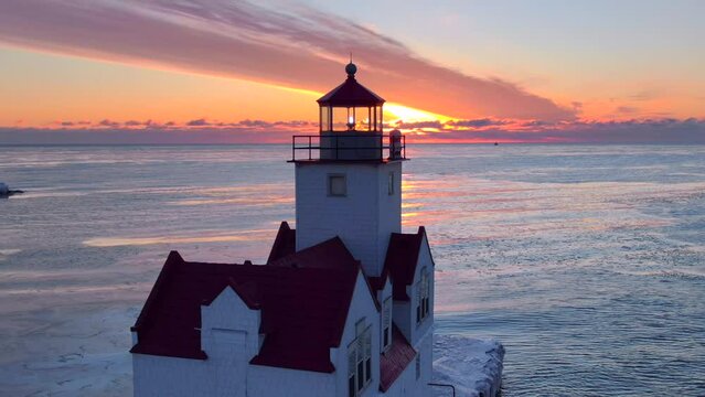 There is amazing beauty in this aerial view of Kewaunee Harbor, clouds on the horizon, waves reflecting the fiery sky, lighthouse beacon alight, Lake Michigan in the Winter just before sunrise. 