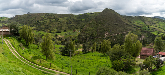Red brick house in a landscape with a lot of green due to vegetation and small hills around it. Colombia.