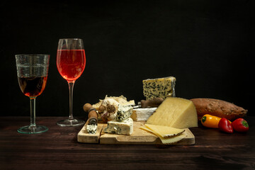 Still life with a table full of delicious assorted cheeses on a board with knives, tomatoes, strong...