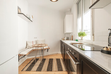 Kitchen with dark wood furniture with white marble top, ceramic hob, aluminum window and carpet on the floor