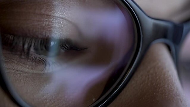 Social Feed Reflection On Eyeball And Glasses. This is close up macro type of shot of woman&rsquo;s eye looking at smart device and reading social information stream online.