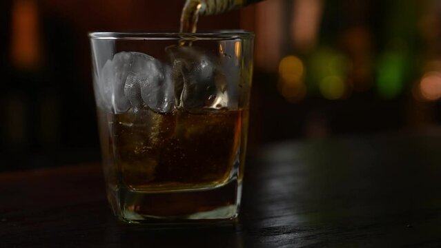 whiskey pouring into glass of ice