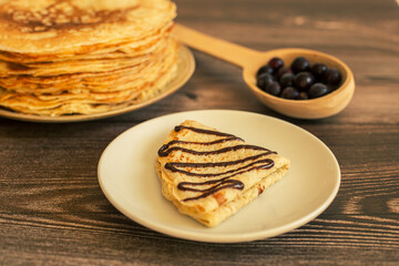 Delicious pancakes with chocolate sauce fresh blueberries on a rustic wooden table. Rustic brown table. 