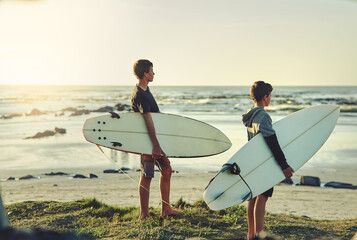 Theyve got a case of surfing fever. Shot of two young brothers holding their surfboards while...