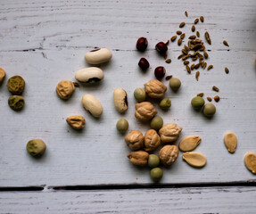 Assorted seeds including bean, pea, pumpkin, anise, bald cypress lay on old whitewashed table
