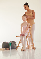 Success is where preparation and opportunity meet. Shot of a ballerina helping a younger girl style...