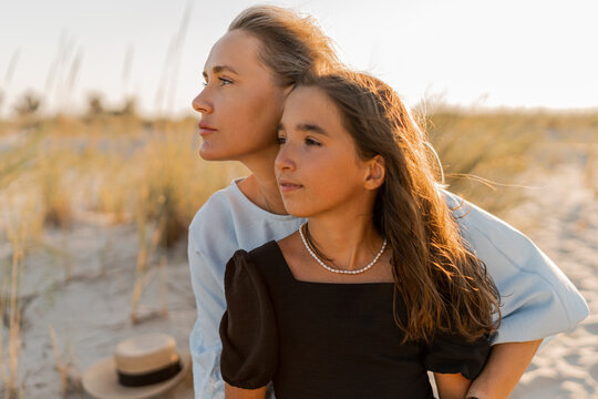 Outdoor fashion photo of beautiful family. Mother and doughter posing on the beach.
