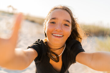 Amazing girl having fun and making self portrait by camera on sunny beach.