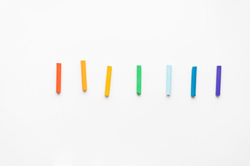 A set of pastel pencils of all colors of the rainbow scattered on a white background. place under the text
