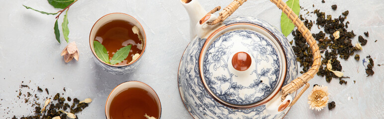 Asian teapot with herbal tea on light background.